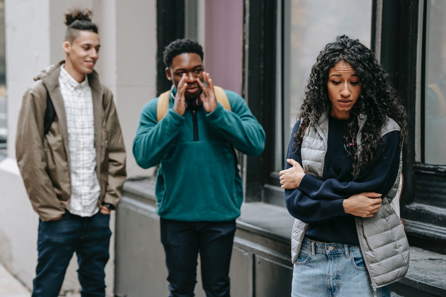 diverse guys scoffing at ethnic female teenager on street